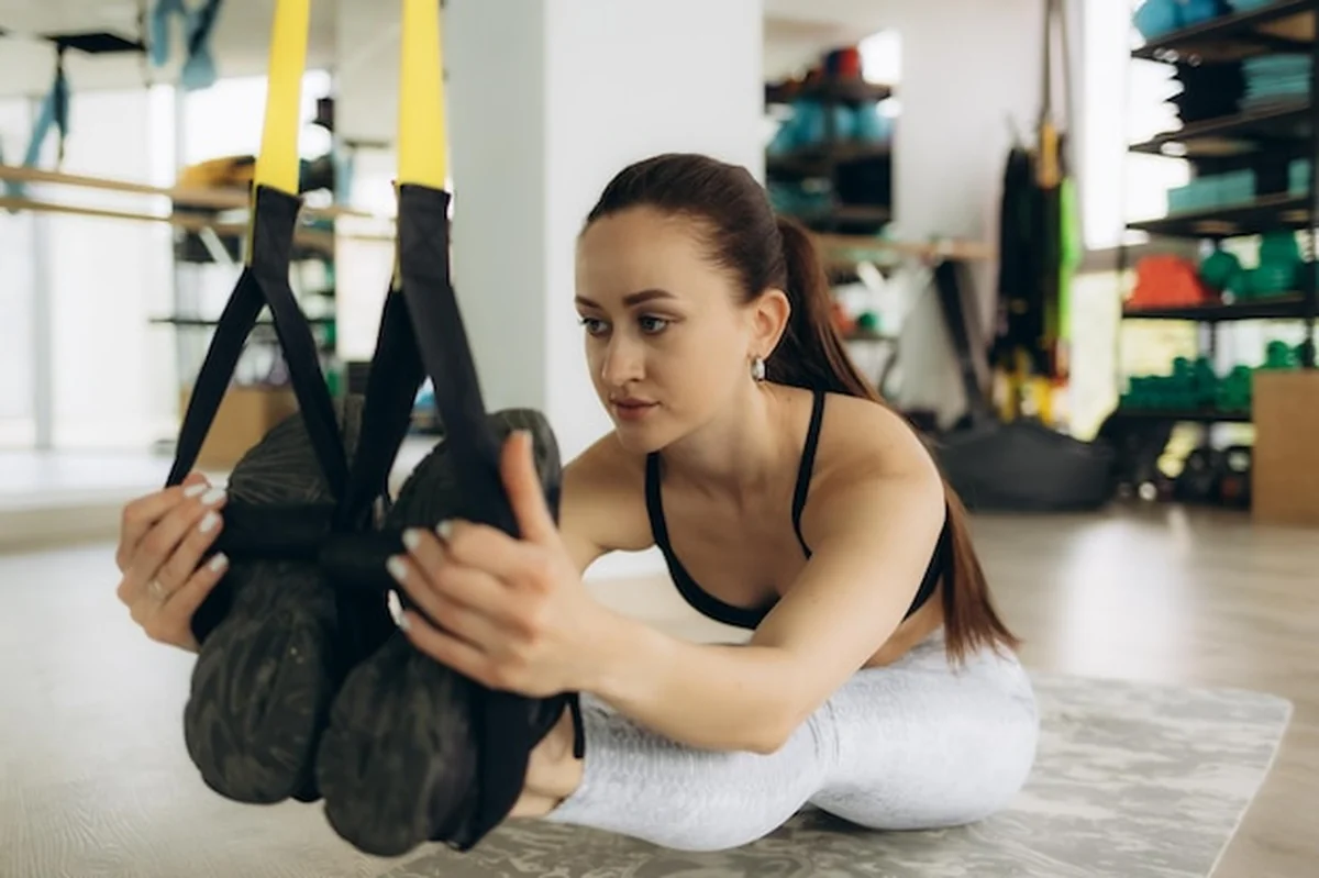 Kobieta ćwiczy rozciągające ćwiczenia z pasami zawieszonymi